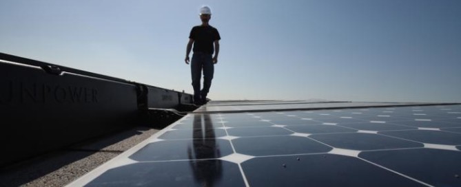 An installer is surveying Precis Solar Panels on a roof.